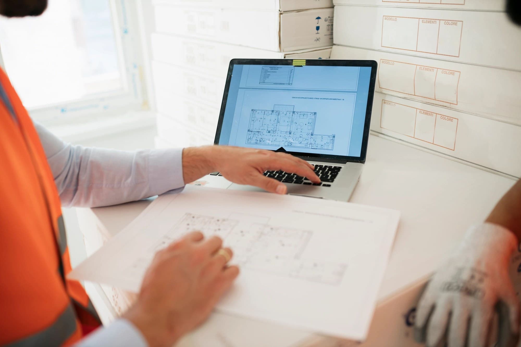 Construction designers reviewing technical drawings and digital plans during design risk coordination